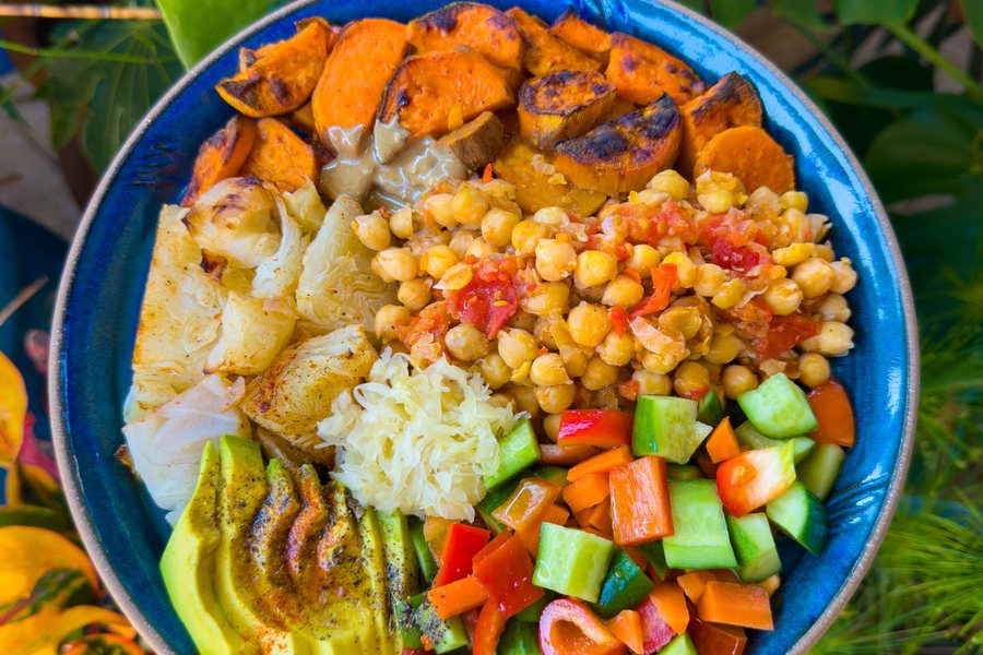 A large bowl of chickpeas with roasted cabbage, sweet potato, avocado and a fresh chopped salad.