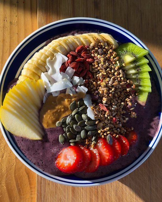 An acai bowl topped with kiwi, strawberries, granola and pumpkin seeds.