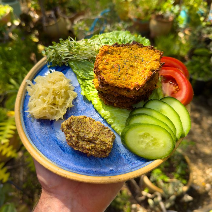 Quinoa veggie patties on a blue plate with cucumber, tomato and sauerkraut.